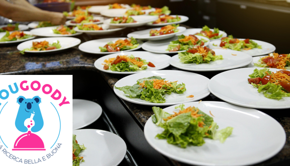Una tavolata di piatti contenenti insalata e il logo YouGoody - la ricerca bella e buona in sovraimpressione
