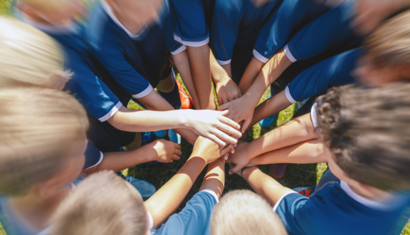 squadra di bambini di cui si vedono le mani unite