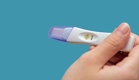 Mano femminile che tiene un test di gravidanza positivo