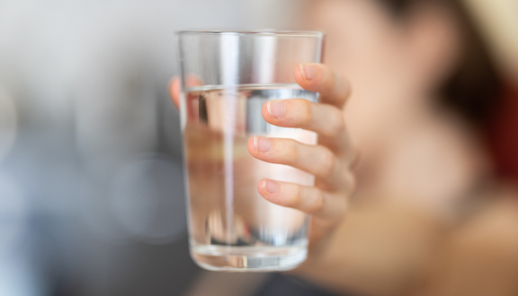 una mano femminile che regge un bicchiere di acqua